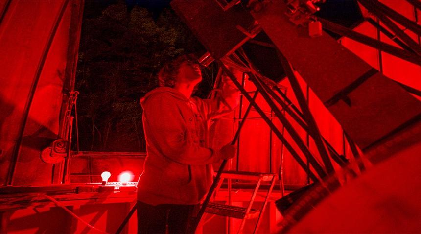 露营者通过天文台的高倍望远镜观看